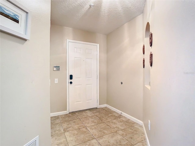 doorway with light tile patterned flooring and a textured ceiling