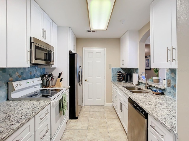 kitchen with appliances with stainless steel finishes, white cabinetry, light stone countertops, and sink