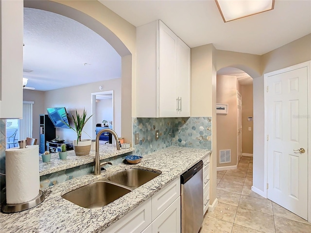 kitchen with light stone countertops, sink, dishwasher, white cabinets, and decorative backsplash