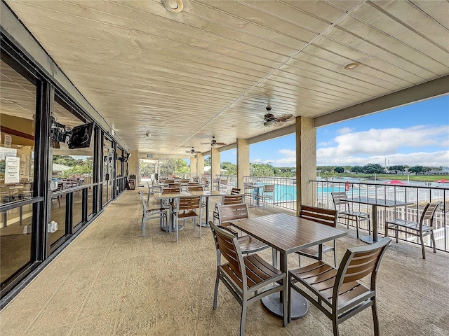 view of patio with a water view and ceiling fan