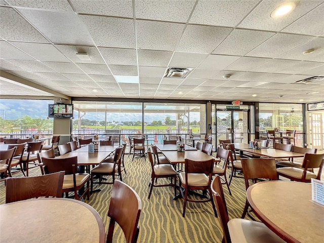 carpeted dining room featuring a wall of windows and a paneled ceiling