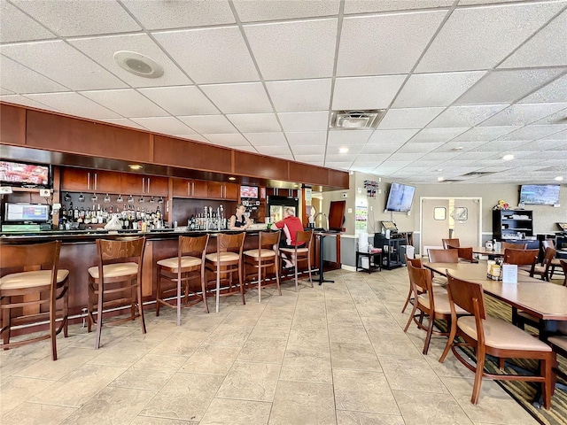 bar featuring light tile patterned floors and a drop ceiling