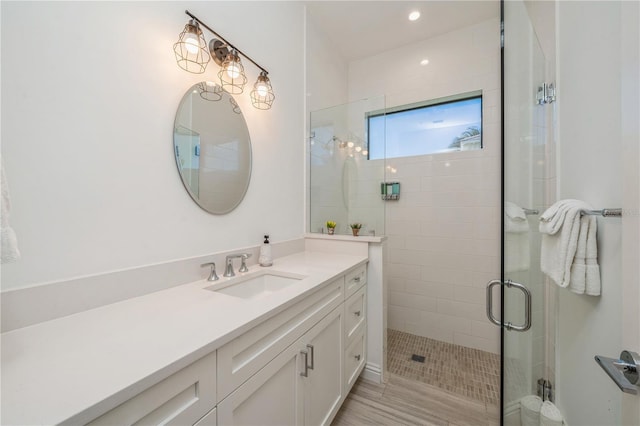 bathroom featuring an enclosed shower, vanity, and wood-type flooring