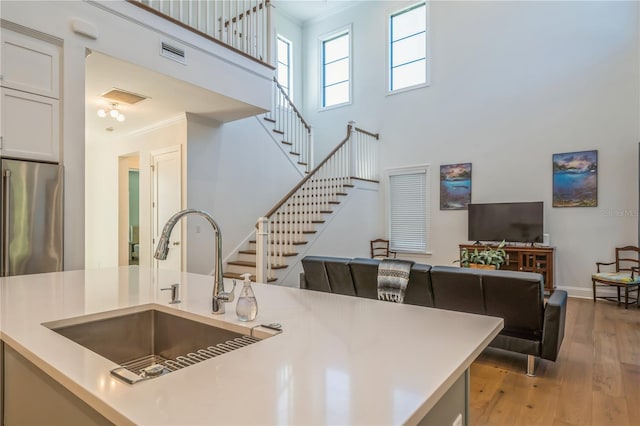 kitchen with ornamental molding, light wood-type flooring, sink, and stainless steel fridge