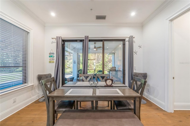 dining space with light hardwood / wood-style flooring and crown molding