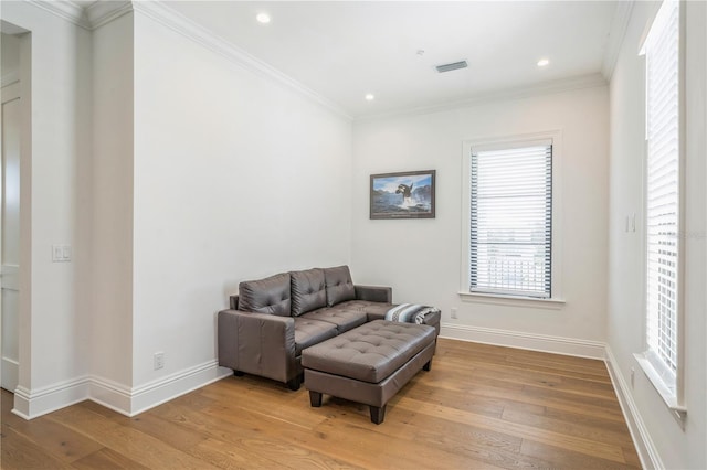 living area featuring light wood-type flooring and crown molding