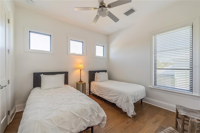 bedroom featuring dark hardwood / wood-style flooring, multiple windows, and ceiling fan