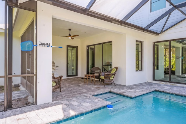 view of swimming pool with glass enclosure, a patio area, and ceiling fan