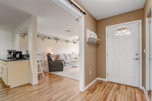 foyer with a textured ceiling, light hardwood / wood-style floors, and ceiling fan