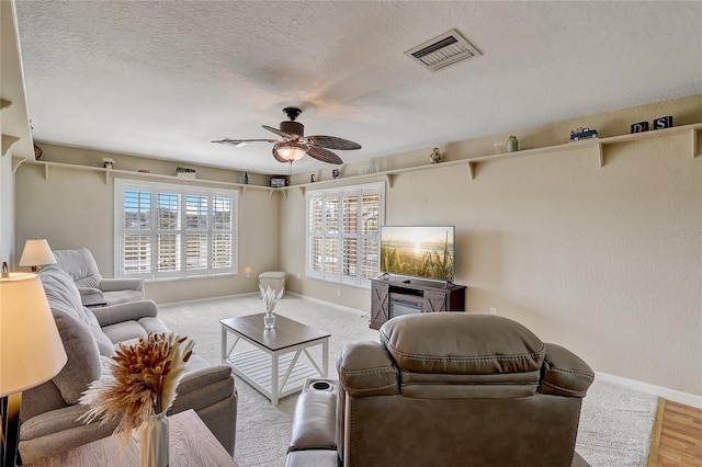 living room with light hardwood / wood-style flooring, a textured ceiling, and ceiling fan