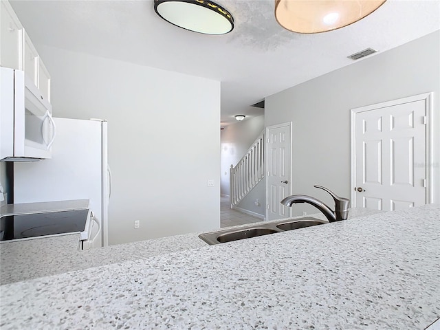 kitchen featuring white cabinetry, sink, light stone counters, kitchen peninsula, and range