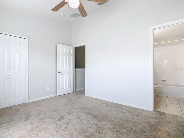 unfurnished bedroom featuring ceiling fan, light colored carpet, connected bathroom, and a closet