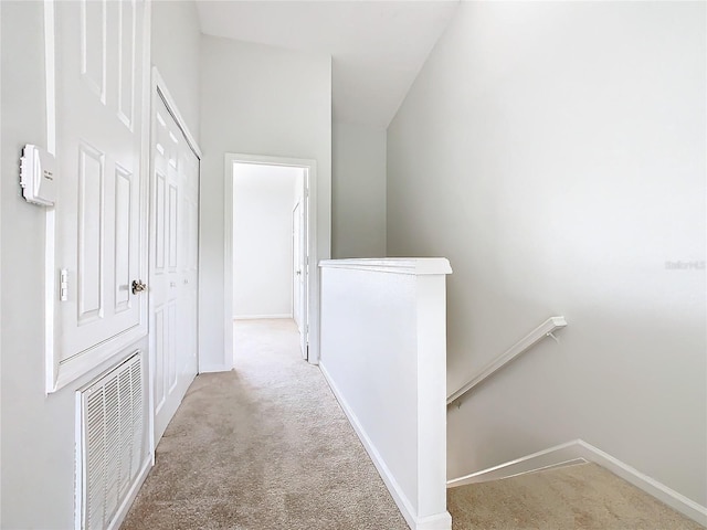 corridor featuring light carpet and vaulted ceiling