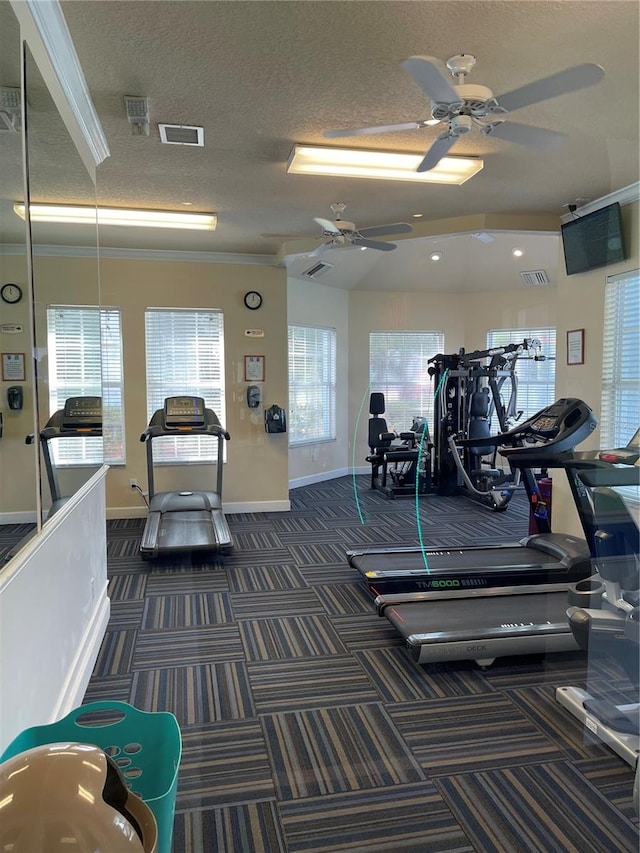 workout area featuring crown molding, ceiling fan, a healthy amount of sunlight, and dark carpet