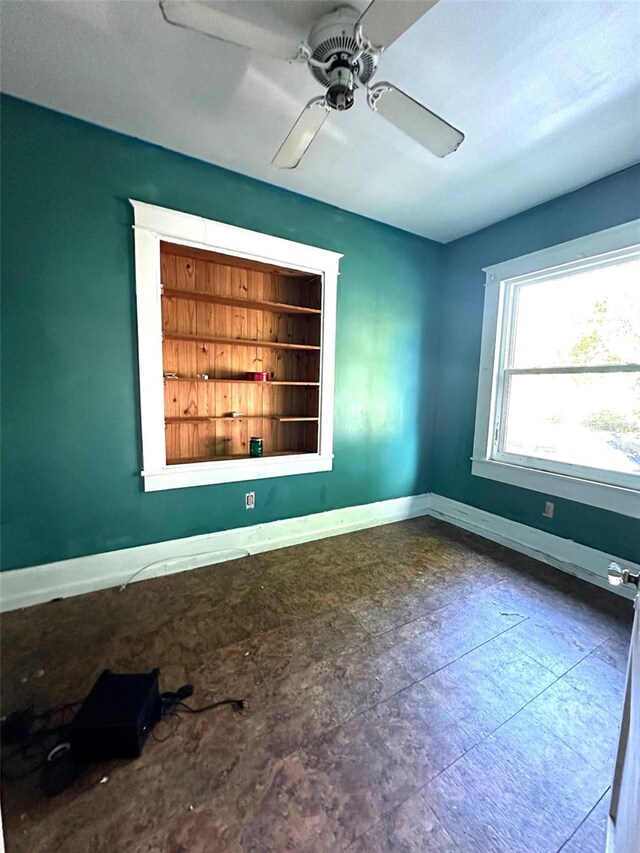 empty room featuring ceiling fan and built in shelves