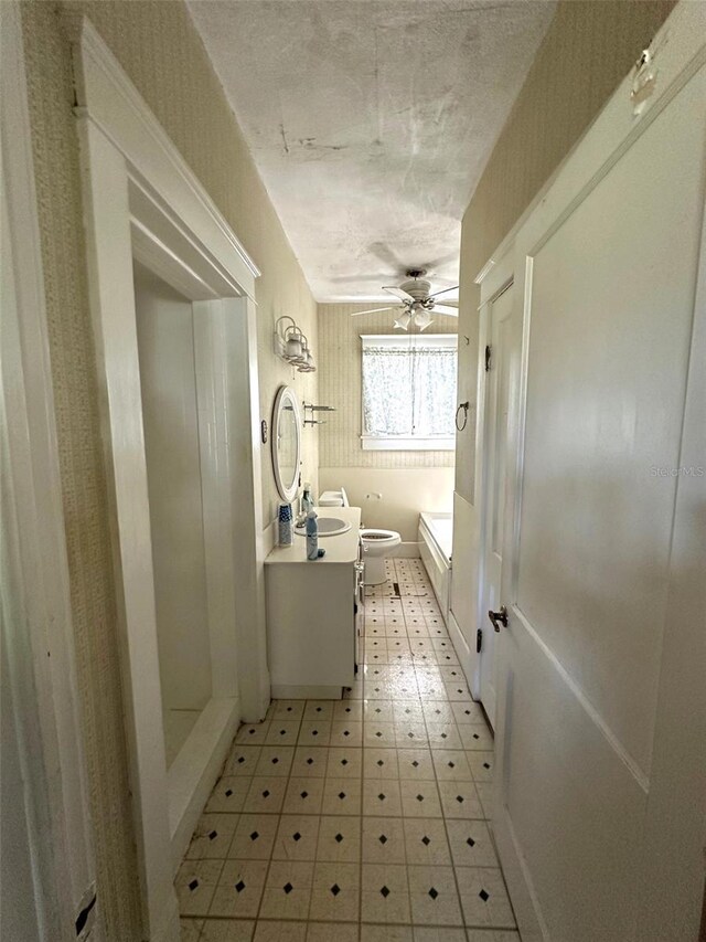 bathroom with a textured ceiling, toilet, ceiling fan, walk in shower, and vanity