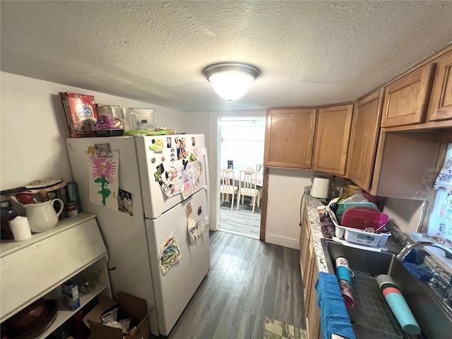 kitchen featuring dark wood-type flooring, white fridge, and a textured ceiling