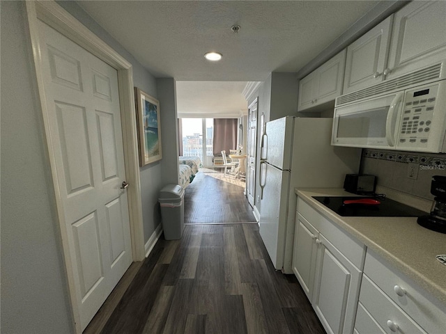 2700 N Atlantic Ave Unit 1003, Daytona Beach, FL 32118 - kitchen with white microwave, dark wood-style floors, white cabinets, black electric stovetop, and light countertops