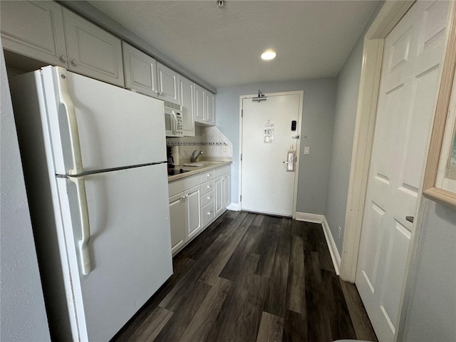 kitchen featuring white appliances, white cabinetry, dark hardwood / wood-style flooring, and sink