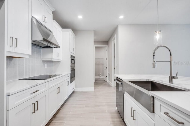 kitchen with white cabinetry, light stone countertops, sink, stainless steel appliances, and pendant lighting