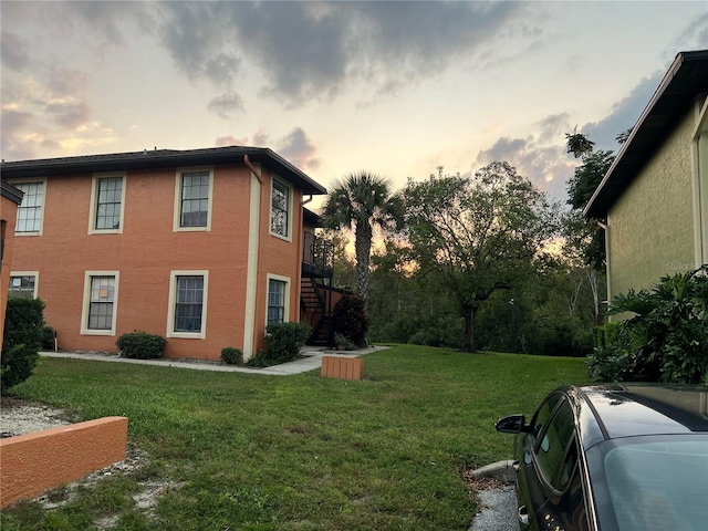 property exterior at dusk featuring a lawn