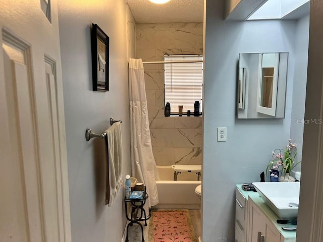 full bathroom featuring a skylight, a textured ceiling, shower / bath combo, toilet, and vanity