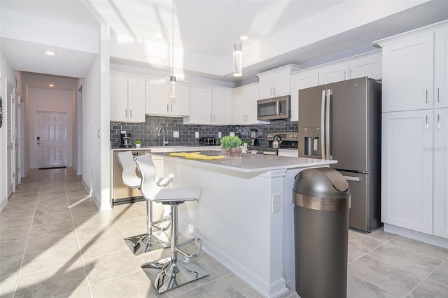 kitchen featuring appliances with stainless steel finishes, decorative backsplash, white cabinetry, and a kitchen island