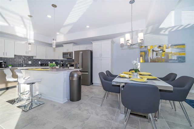 kitchen with a center island, stainless steel appliances, pendant lighting, white cabinets, and decorative backsplash