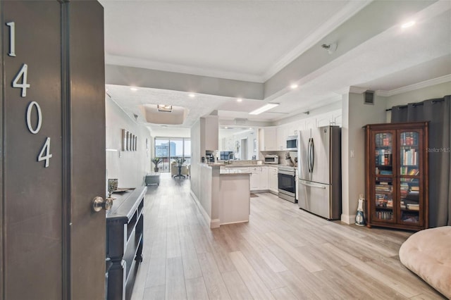 kitchen with kitchen peninsula, white cabinets, light wood-type flooring, ornamental molding, and stainless steel appliances