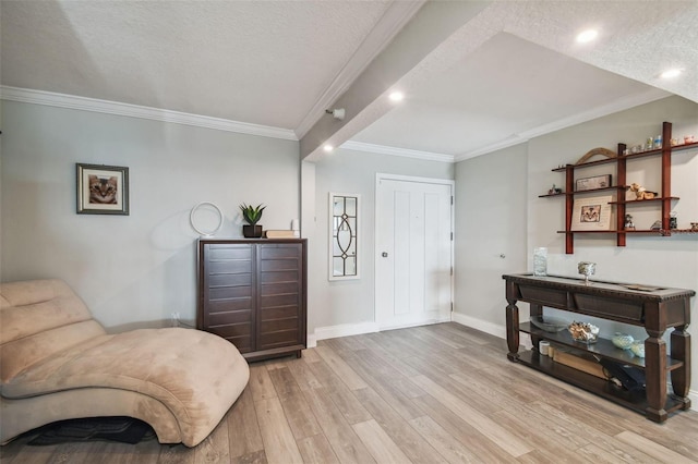 living area with a textured ceiling, ornamental molding, and light wood-type flooring