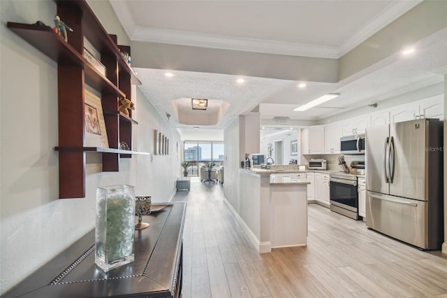 kitchen with appliances with stainless steel finishes, kitchen peninsula, white cabinets, and light hardwood / wood-style floors