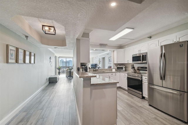 kitchen featuring white cabinetry, kitchen peninsula, a textured ceiling, and stainless steel appliances