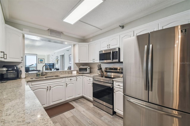 kitchen with light hardwood / wood-style flooring, stainless steel appliances, sink, light stone countertops, and white cabinetry