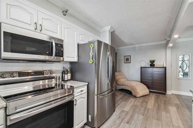 kitchen with light hardwood / wood-style floors, crown molding, appliances with stainless steel finishes, and white cabinets