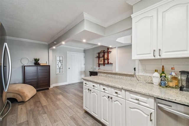 kitchen featuring white cabinets, hardwood / wood-style floors, appliances with stainless steel finishes, light stone countertops, and crown molding