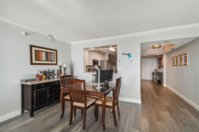 dining space featuring crown molding, hardwood / wood-style flooring, and a textured ceiling