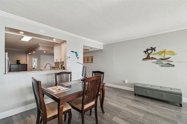 dining room with ornamental molding, hardwood / wood-style floors, and a textured ceiling