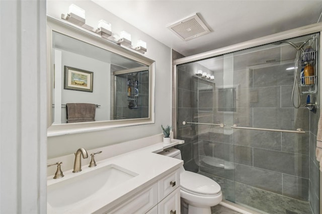 bathroom featuring vanity, a shower with shower door, and toilet