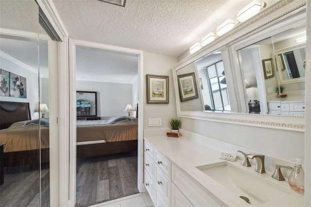 bathroom with vanity, ornamental molding, hardwood / wood-style flooring, and a textured ceiling