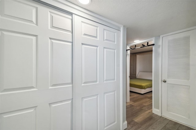 corridor with dark wood-type flooring and a textured ceiling