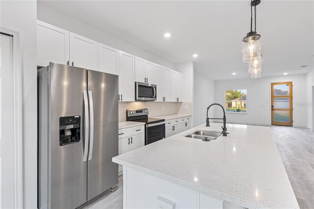 kitchen featuring white cabinetry, stainless steel appliances, sink, and hanging light fixtures