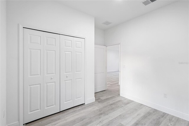 unfurnished bedroom featuring light wood-type flooring and a closet