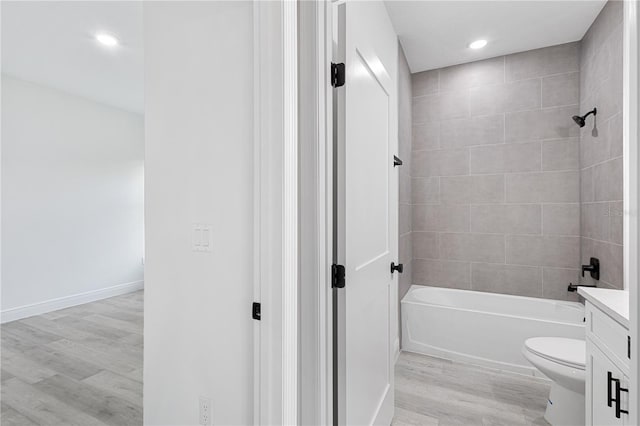 full bathroom with vanity, toilet, hardwood / wood-style flooring, and tiled shower / bath combo