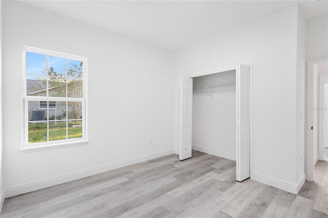 unfurnished bedroom featuring light hardwood / wood-style flooring, multiple windows, and a closet