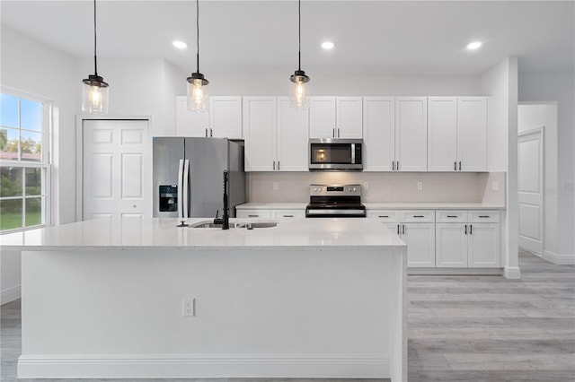 kitchen featuring white cabinetry, hanging light fixtures, and stainless steel appliances