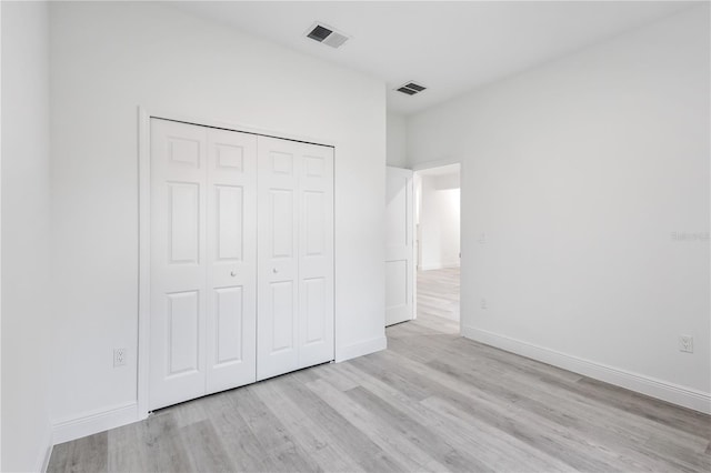 unfurnished bedroom with a closet and light wood-type flooring