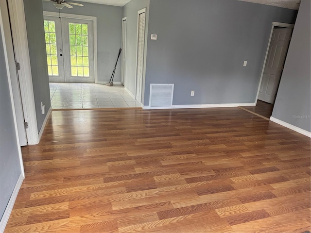 empty room with light hardwood / wood-style floors, ceiling fan, a textured ceiling, and french doors