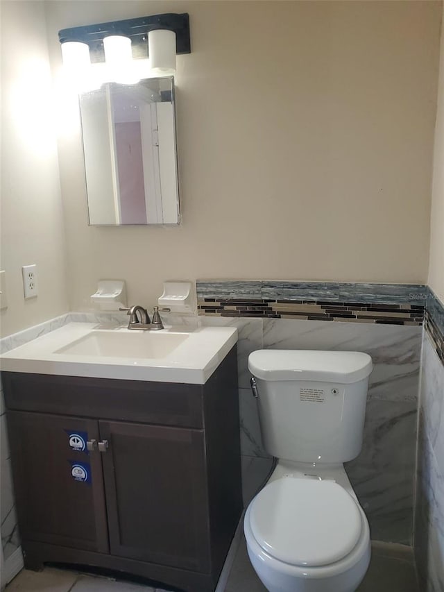 bathroom with tile walls, toilet, and vanity