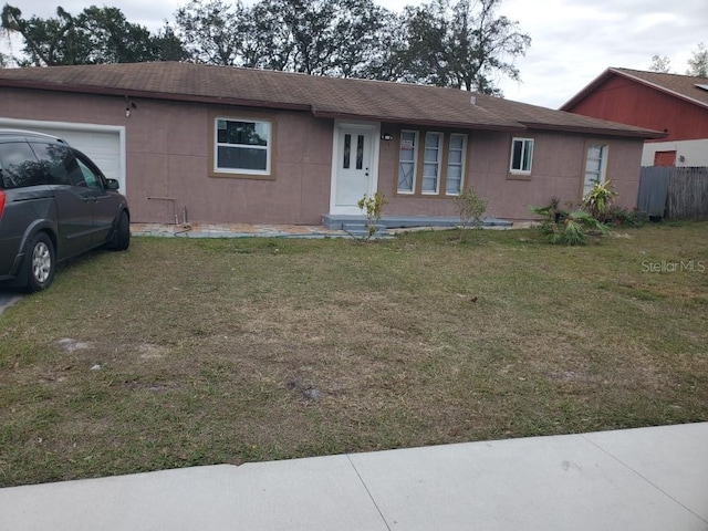 ranch-style home featuring stucco siding, a front yard, and an attached garage