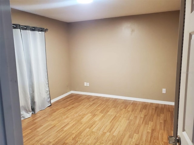 spare room featuring light wood-type flooring and baseboards